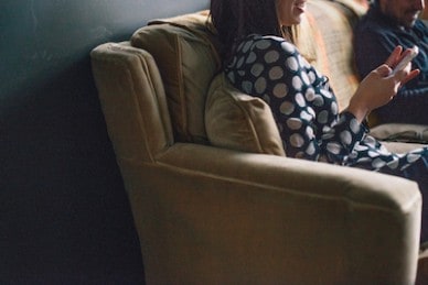 woman on cell phone sitting on couch